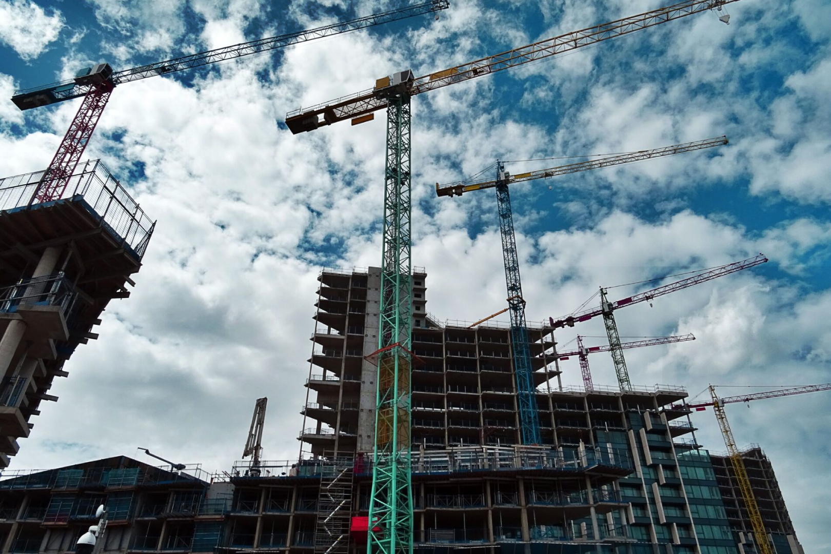 A group of cranes in front of a building under construction.